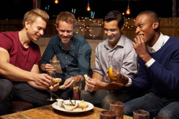 Group Of Male Friends Enjoying Night Out At Rooftop Bar