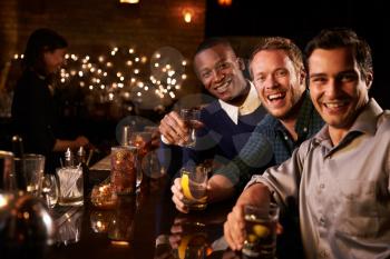 Portrait Of Male Friends Enjoying Night Out At Cocktail Bar