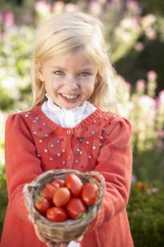 Young girl posing with tomatoes in garden