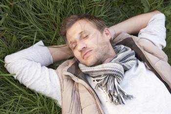 Young man napping alone on grass