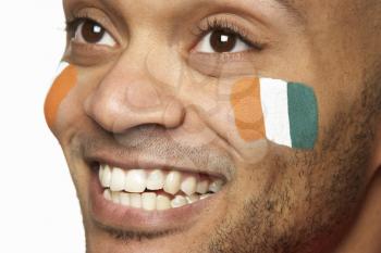 Young Male Sports Fan With Ivory Coast Flag Painted On Face
