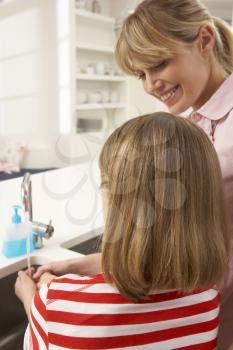 Mother And Daughter Washing Hands At Kitchen Sink