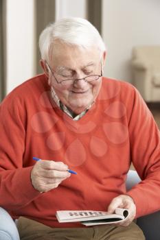 Senior Man Relaxing In Chair At Home Completing Crossword