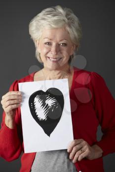 Senior woman holding ink drawing of heart