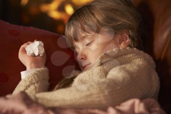 Sick Girl With Cold Resting On Sofa By Cosy Log Fire
