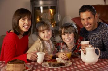 Portrait Of Family Enjoying Tea And Cake By Cosy Log Fire