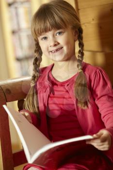 Young Girl Sitting On Wooden Seat Reading Book