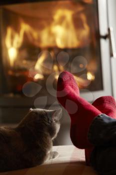 Close Up Of Mans Feet Relaxing By Cosy Log Fire With Cat