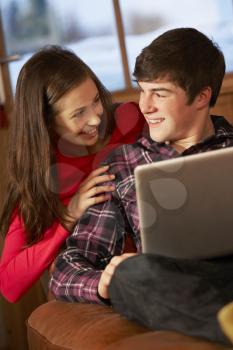 Teenage Couple Relaxing On Sofa With Laptop