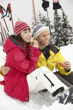 Middle Aged Couple Eating Sandwich On Ski Holiday In Mountains