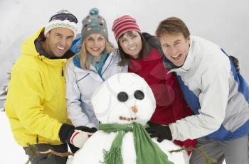 Group Of Friends Building Snowman On Ski Holiday In Mountains