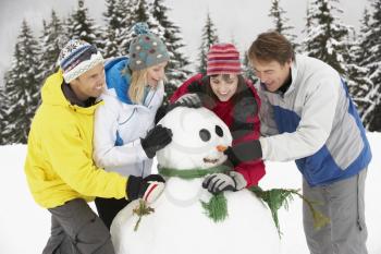 Group Of Friends Building Snowman On Ski Holiday In Mountains