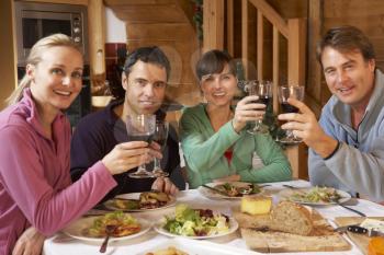Group Of Friends Enjoying Meal In Alpine Chalet Together