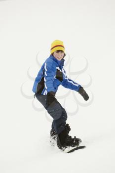 Young Boy Snowboarding Down Slope On Holiday In Mountain