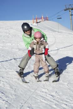 Father Teaching Daughter To Ski Whilst On Holiday In Mountains