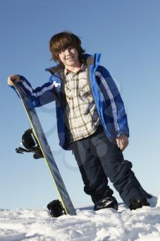 Young Boy With Snowboard On Ski Holiday In Mountains