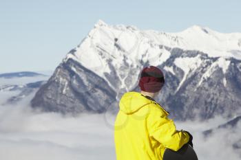 Teenage Snowboarder Admiring Mountain View Whilst On Ski Holiday In Mountains