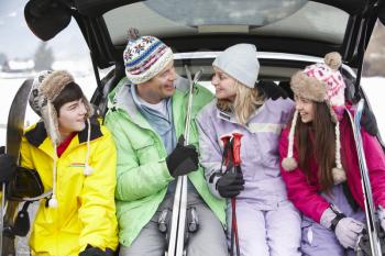 Teenage Family Sitting In Boot Of Car With Skis