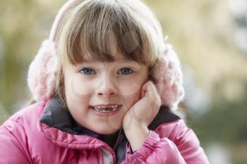 Outdoor Portrait Of Young Girl Wearing Winter Clothes And Earmuffs