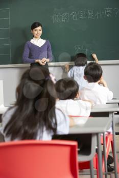 Female Pupil Writing On Blackboard In Chinese School Classroom