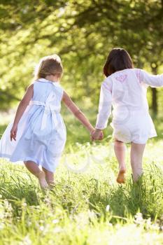 Two Young Girls Walking Through Summer Field Together