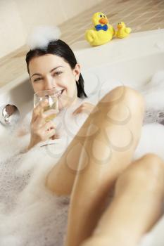 Woman Relaxing With Glass Of Wine In Bubble Filled Bath