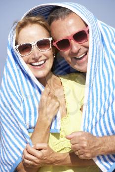 Senior Couple Sheltering From Sun On Beach Holiday