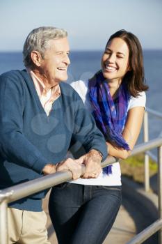 Senior Man With Adult Daughter Looking Over Railing At Sea