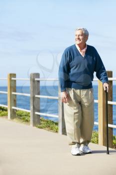 Senior Man Walking Along Path By The Sea