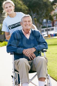 Teenage Volunteer Pushing Senior Man In Wheelchair