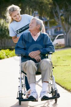 Teenage Volunteer Pushing Senior Man In Wheelchair
