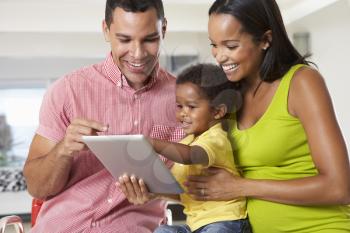 Family Using Digital Tablet In Kitchen Together