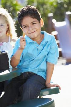 Elementary Pupil Sitting At Table Eating Lunch