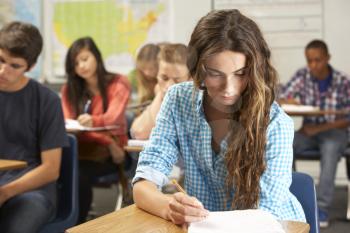 Female Pupil Studying At Desk In Classroom