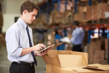 Manager In Warehouse Checking Boxes Using Digital Tablet