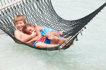Brother And Sister Relaxing In Beach Hammock