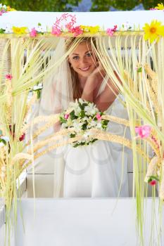 Bride Sitting Under Decorated Canopy At Wedding