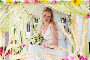 Bride Sitting Under Decorated Canopy At Wedding