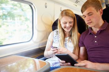 Young Couple Reading E Book On Train Journey