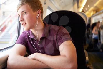 Young Man Listening To Music On Train Journey