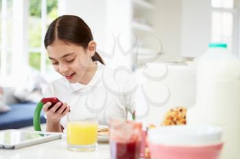 Schoolgirl With Digital Tablet And Mobile At Breakfast