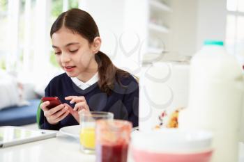 Schoolgirl With Digital Tablet And Mobile At Breakfast