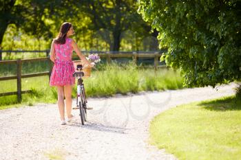Rear View As Woman Pushes Bike Along Country Lane