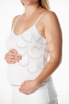 Close Up Studio Portrait Of 4 months Pregnant Woman Wearing White