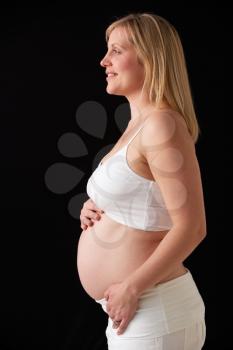 Portrait Of 5 months Pregnant Woman Wearing White On Black Background