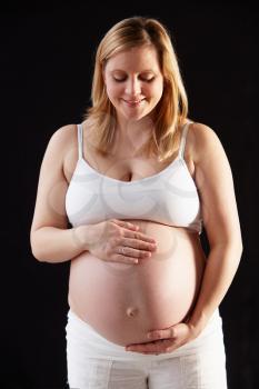 Portrait Of Pregnant Woman Wearing White On Black Background