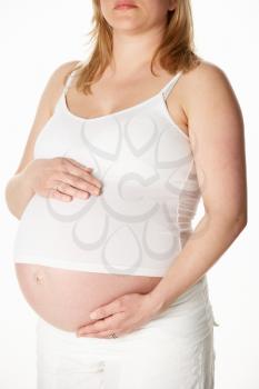 Close Up Studio Portrait Of 8 Months Pregnant Woman Wearing White