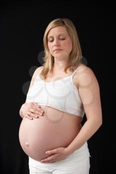 Portrait Of 9 months Pregnant Woman Wearing White On Black Background