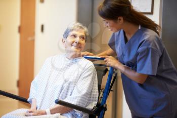 Senior Female Patient Being Pushed In Wheelchair By Nurse