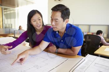 Architects Studying Plans In Modern Office Together